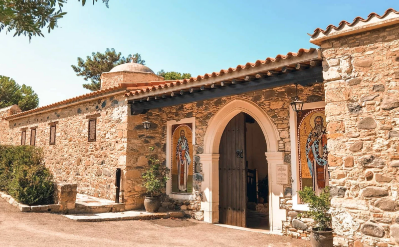 Stone facade with an arched wooden doorway of Agios Irakleidios Monastery in Cyprus.