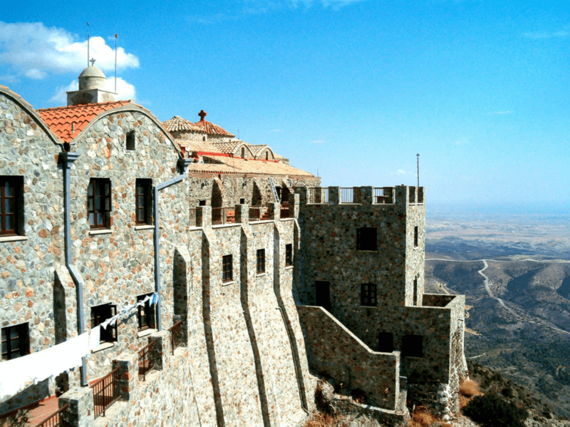 Fortress-like Stavrovouni Monastery of stone buildings perched on a hilltop with a panoramic view over the plains of Cyprus.