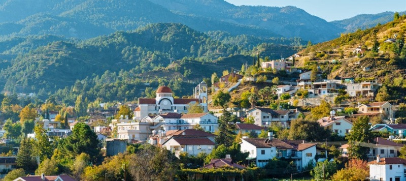 View of Kakopetria village with traditional houses and red-tiled roofs on a green hillside in the Troodos Mountains of Cyprus.