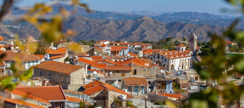 Panoramic view of Lefkara village with traditional houses and red-tiled roofs nestled among green hills in Cyprus.