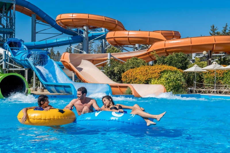 Colourful water slides and a pool with visitors on inflatable rings at Fasouri Watermania waterpark in Cyprus.